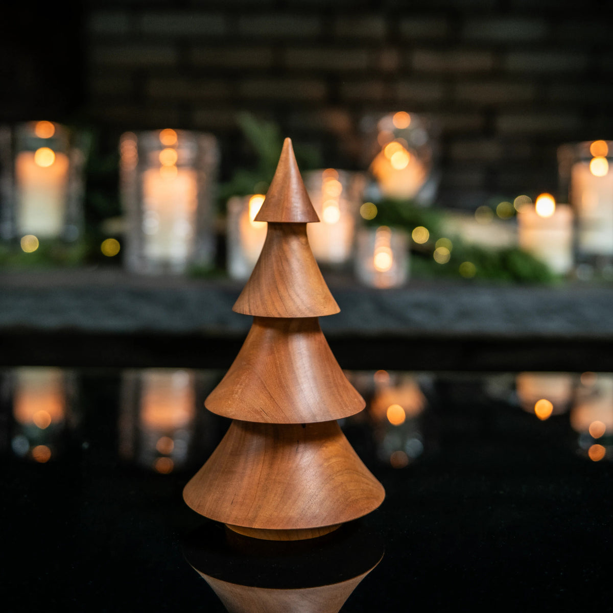 Wooden evergreen tree decoration with stacked cone sections in warm cherry wood finish.