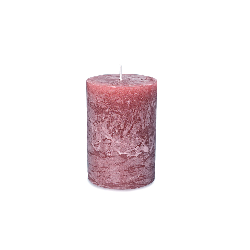 Pink pillar candle with white wick and textured surface.