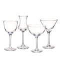 Four clear glass cocktail glasses in different styles with stems and round bases arranged in a row.