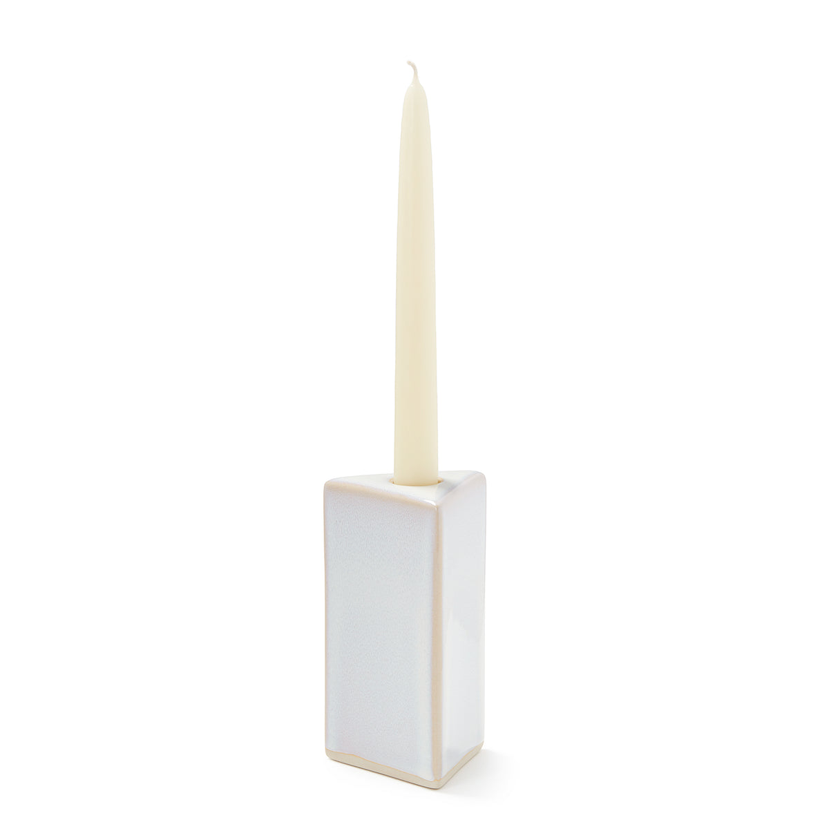 Cream-colored pottery taper candle holder with rectangular base and centered socket, holding a tapered candle.