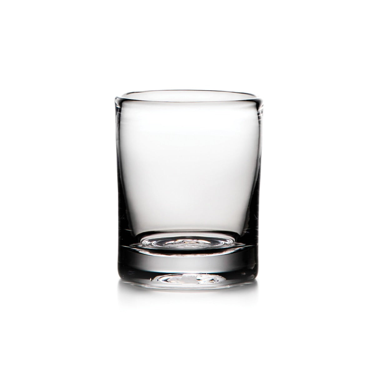 Empty clear glass whiskey tumbler with thick base and weighted bottom on white background.