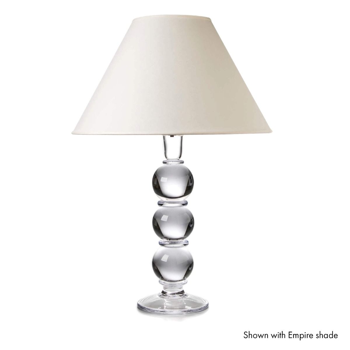 Table lamp with clear glass stacked sphere base and cream-colored empire shade.