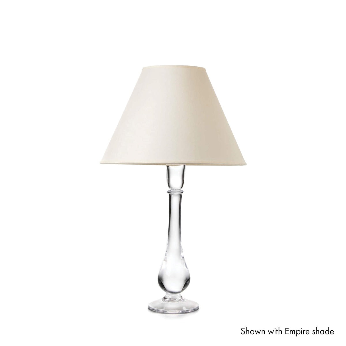 Table lamp with clear glass teardrop-shaped base and cream trapezoid shade.