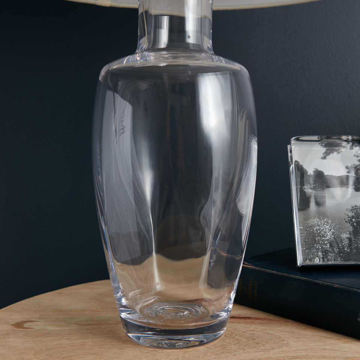 Tall clear glass lamp base with cylindrical shape and natural wood accent ring at top.