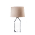 Clear glass bottle-shaped lamp base with beige linen cylindrical shade and metal connector.