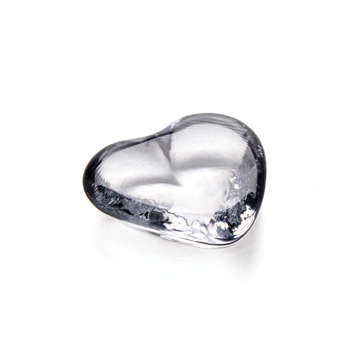Clear glass heart-shaped object with smooth, rounded surfaces and light reflections.