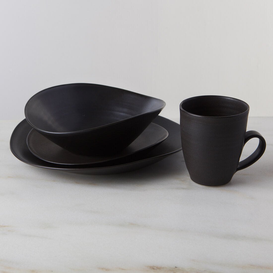 Dark slate dinnerware set with stacked bowls and a cylindrical mug with handle.