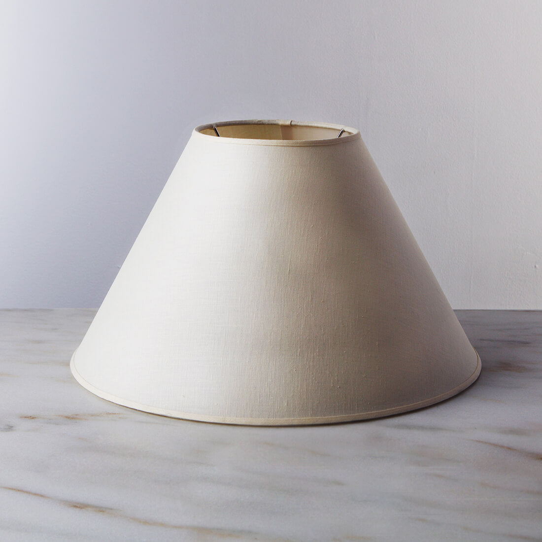 Cream linen empire-shaped lamp shade with brass trim and open top.