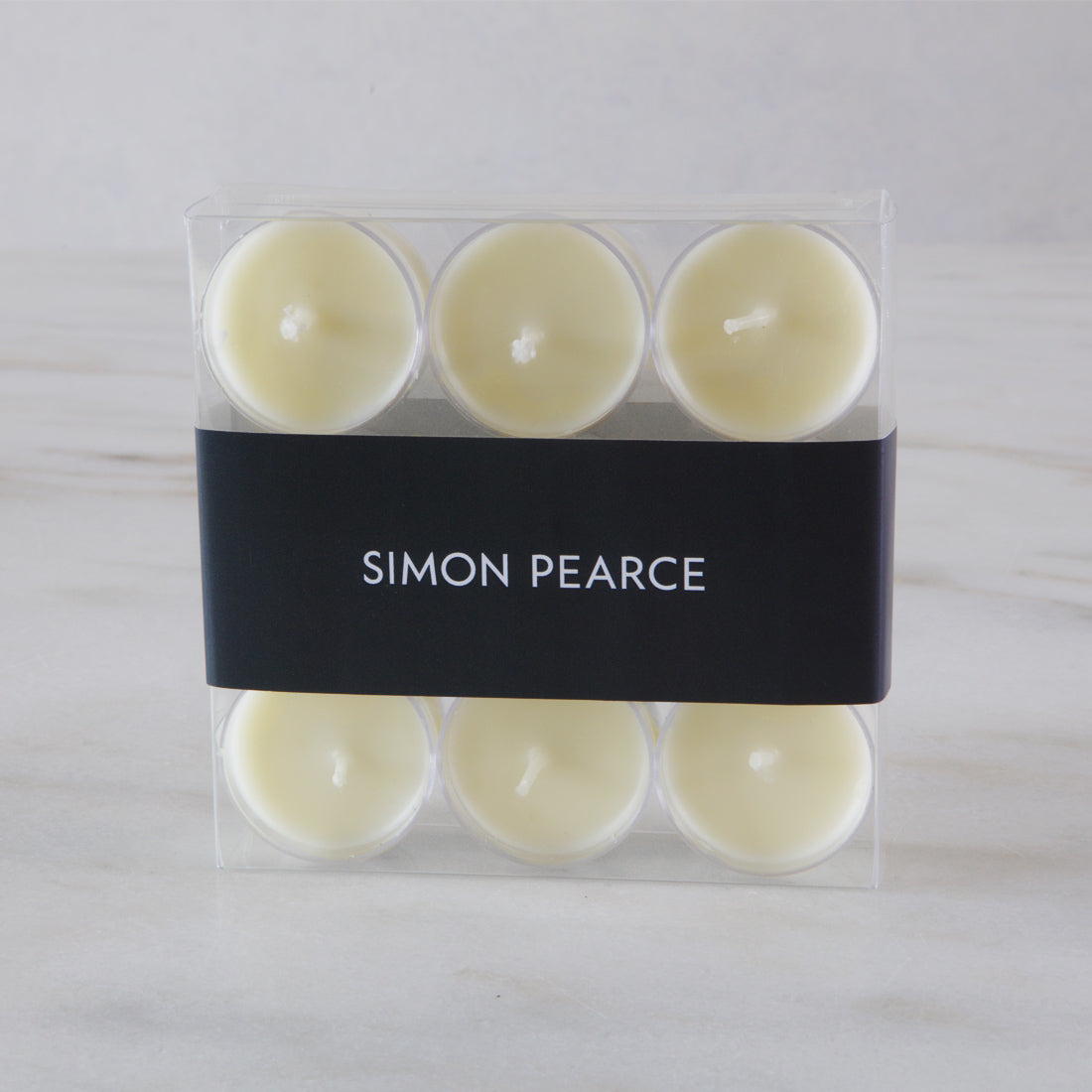 Nine cream-colored tealights in clear plastic cases with black Simon Pearce branded band.