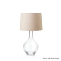 Clear glass teardrop-shaped lamp base with beige linen cylindrical shade.