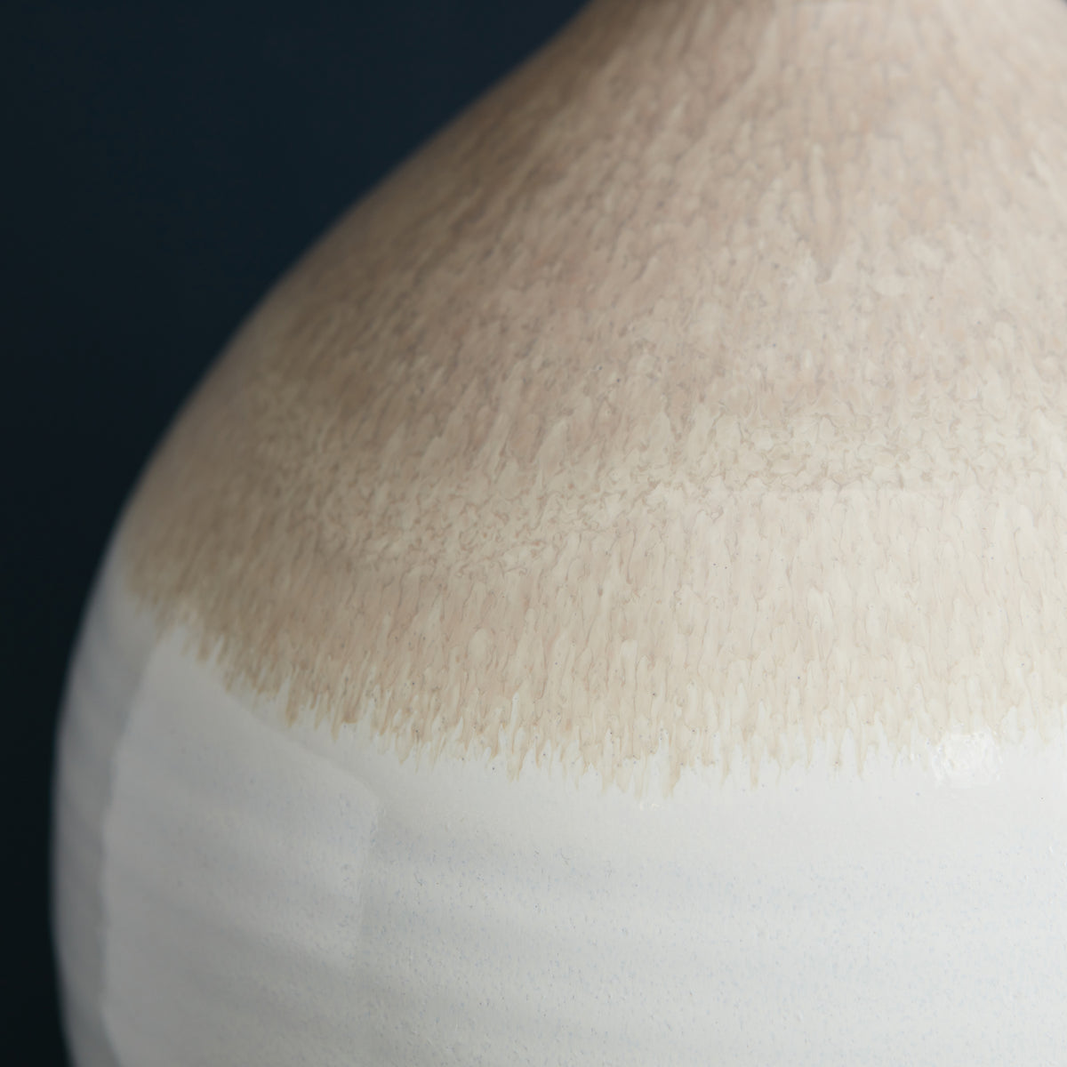 Ceramic lamp base with cream and white reactive glaze finish against dark background.