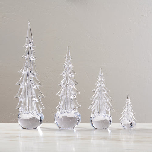 Four clear glass evergreen trees in graduated sizes with pointed tops and faceted branches, displayed in a row.