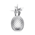 Fresh pineapple with textured skin and leafy crown on white background.