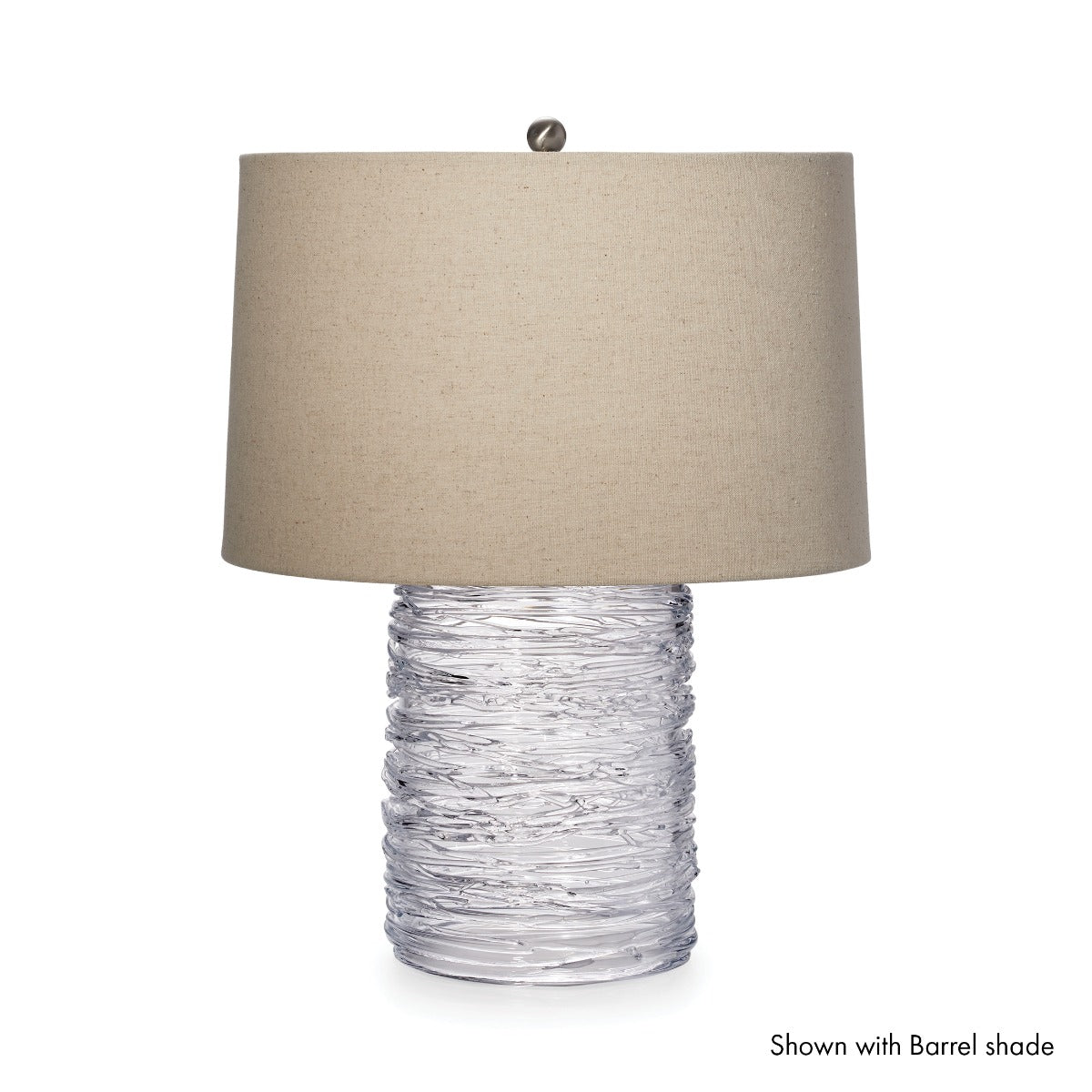 Clear textured glass cylindrical base with beige linen drum shade and metal finial.