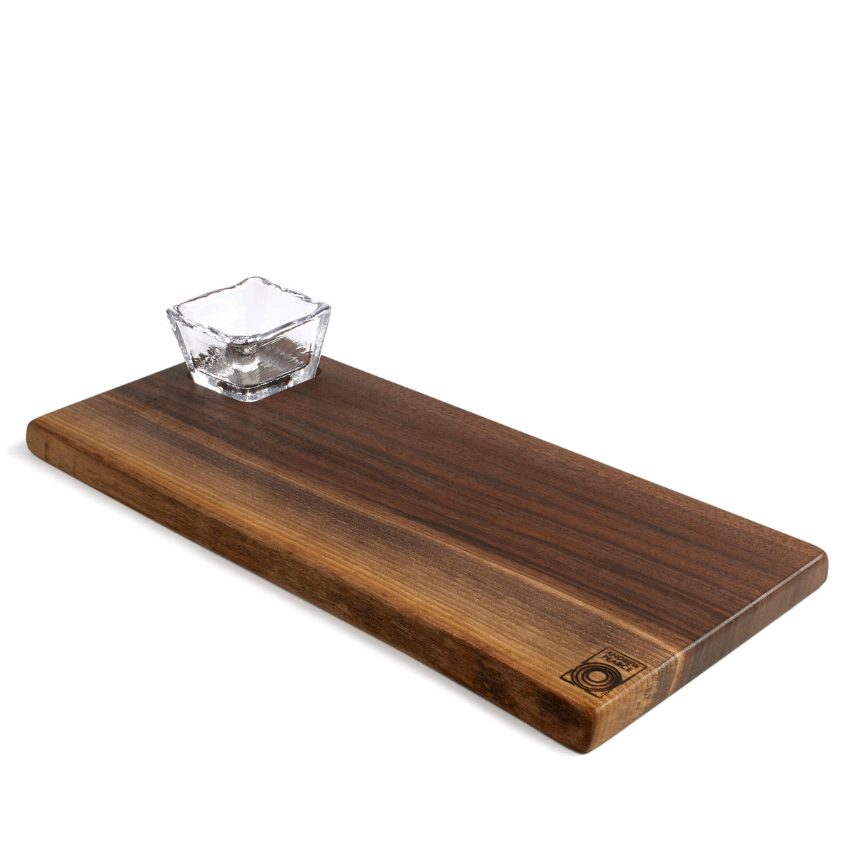 Black walnut live edge board with square glass bowl sitting on surface.