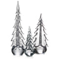 Three clear glass evergreen trees in graduating sizes with pointed tops and layered branch details on solid bases.