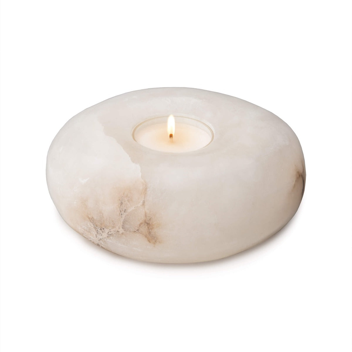 White alabaster tealight holder with lit candle in center well and natural stone variations.