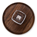 Round wooden chip and dip platter with a square glass bowl insert in the center, viewed from above.
