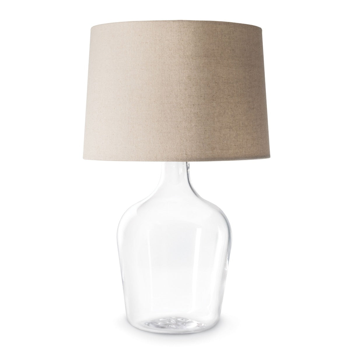 Clear glass bottle-shaped base lamp with tapered beige linen drum shade.