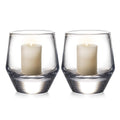 Two clear glass hurricane candle holders, each containing a cream-colored pillar candle with two wicks.