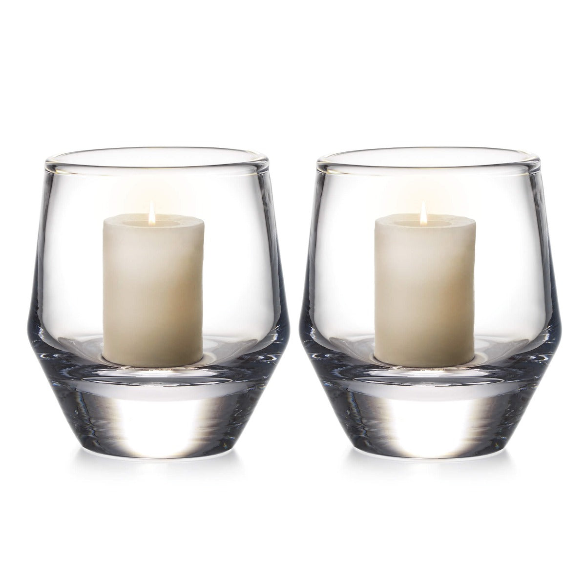 Two clear glass hurricane candle holders, each containing a cream-colored pillar candle with two wicks.