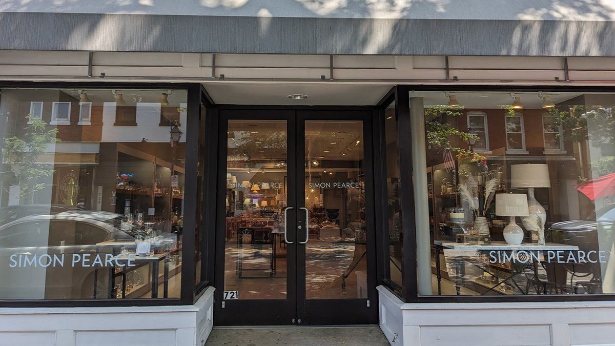 Exterior of the Simon Pearce retail store at 721 King Street in Alexandria, Virginia, featuring large glass display windows with Simon Pearce branding and views of glassware and lamps inside