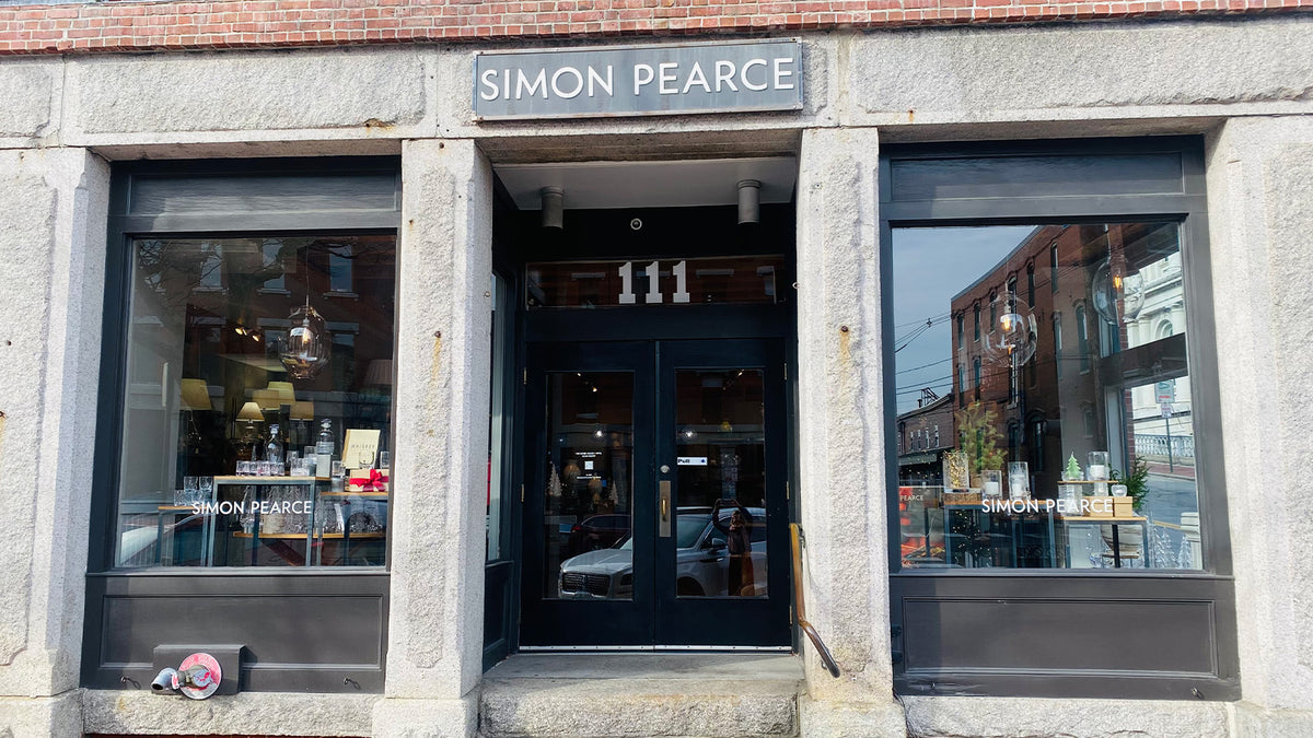 Exterior of the Simon Pearce retail store at 111 Commercial Street in Portland, Maine, set within a granite-faced historic building with dark-framed double doors
