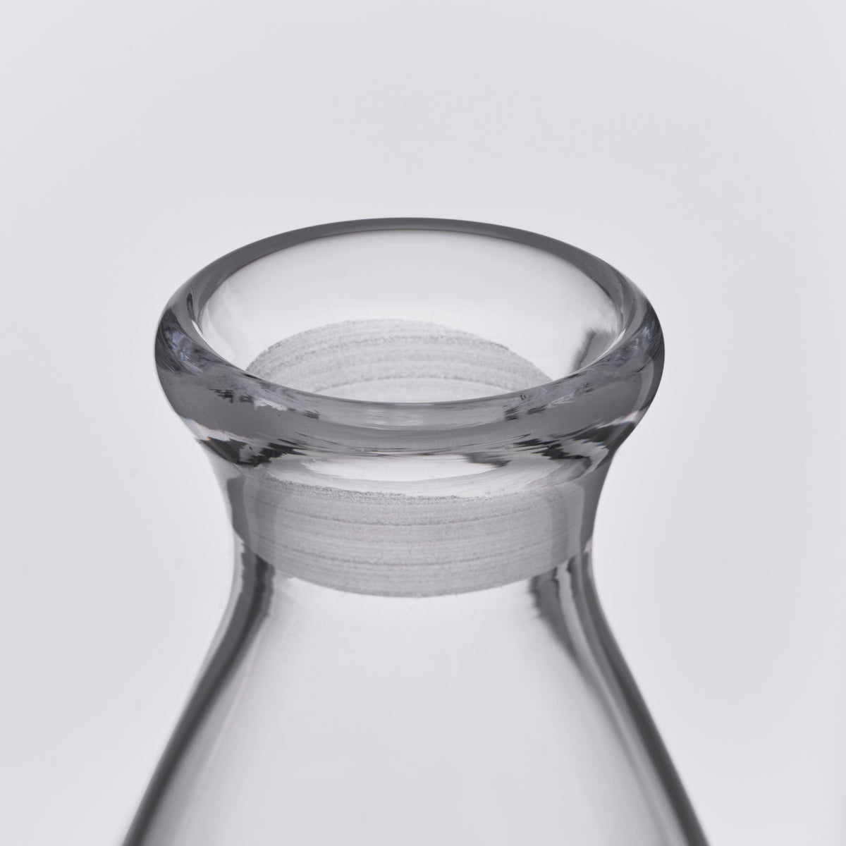 Clear glass decanter with a wide flared rim and gray fabric collar band around the neck.