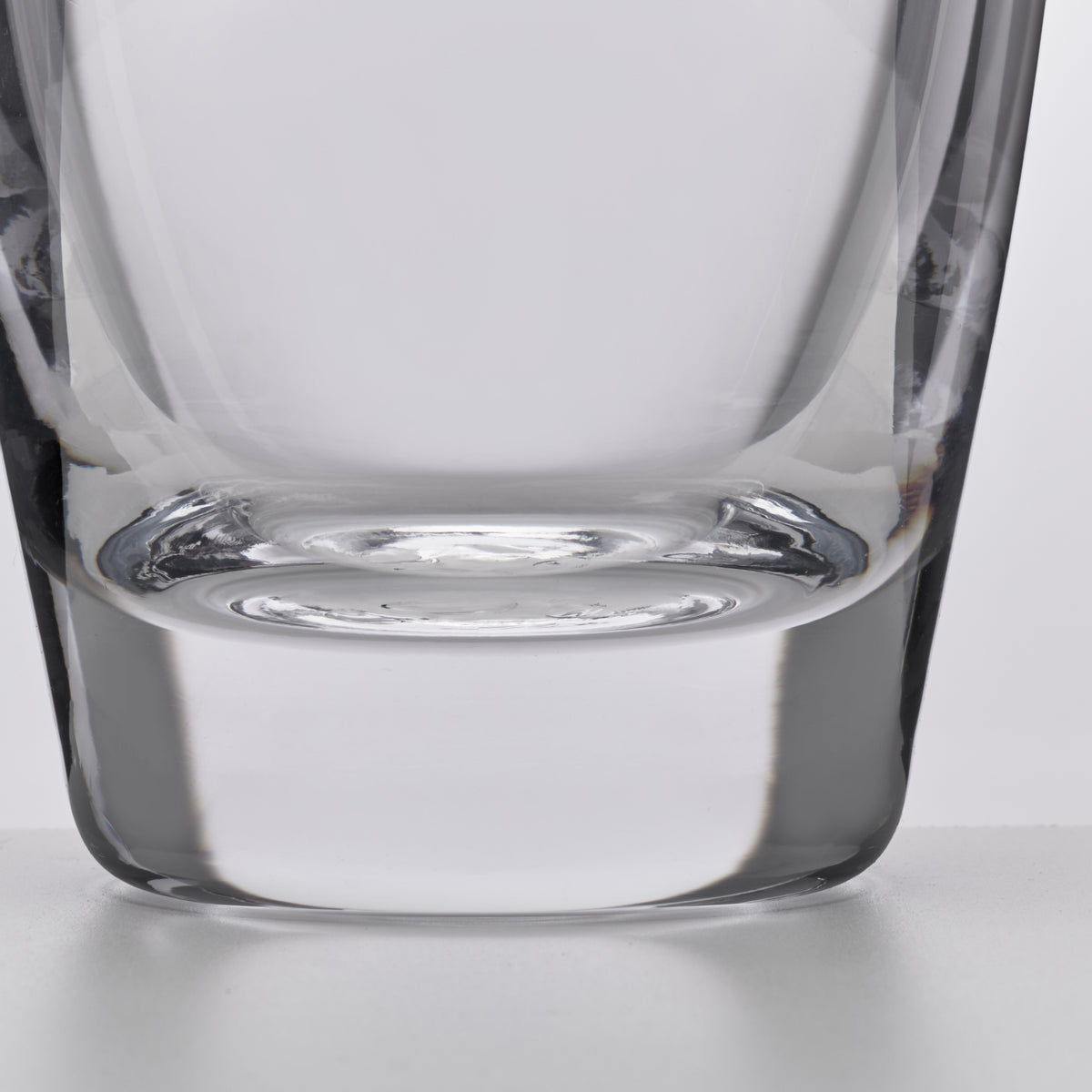 Clear glass decanter with wide base, tapered sides, and curved rim detail, shown from front view.