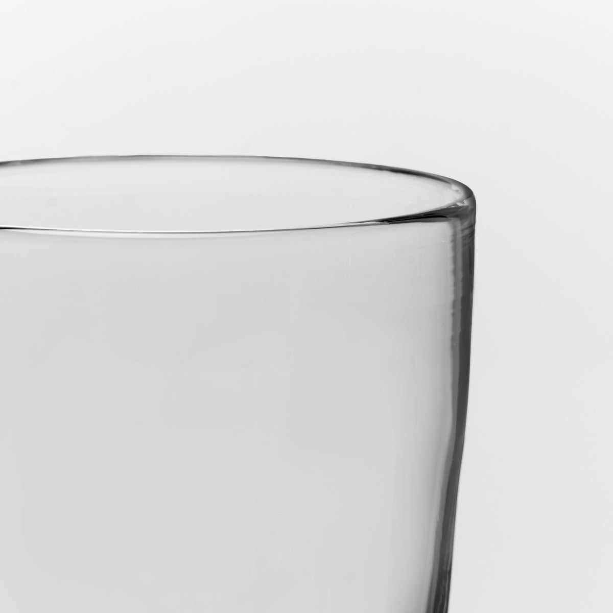 Empty clear glass with rounded rim against white background.