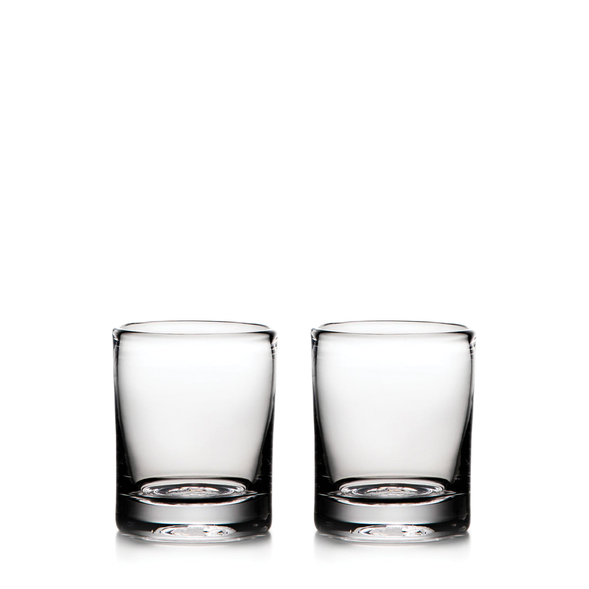 Two clear glass whiskey glasses with thick bases, empty and positioned side by side.