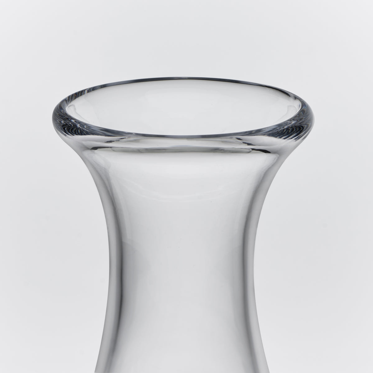Clear glass decanter with curved tapered body and wide flared rim against white background.