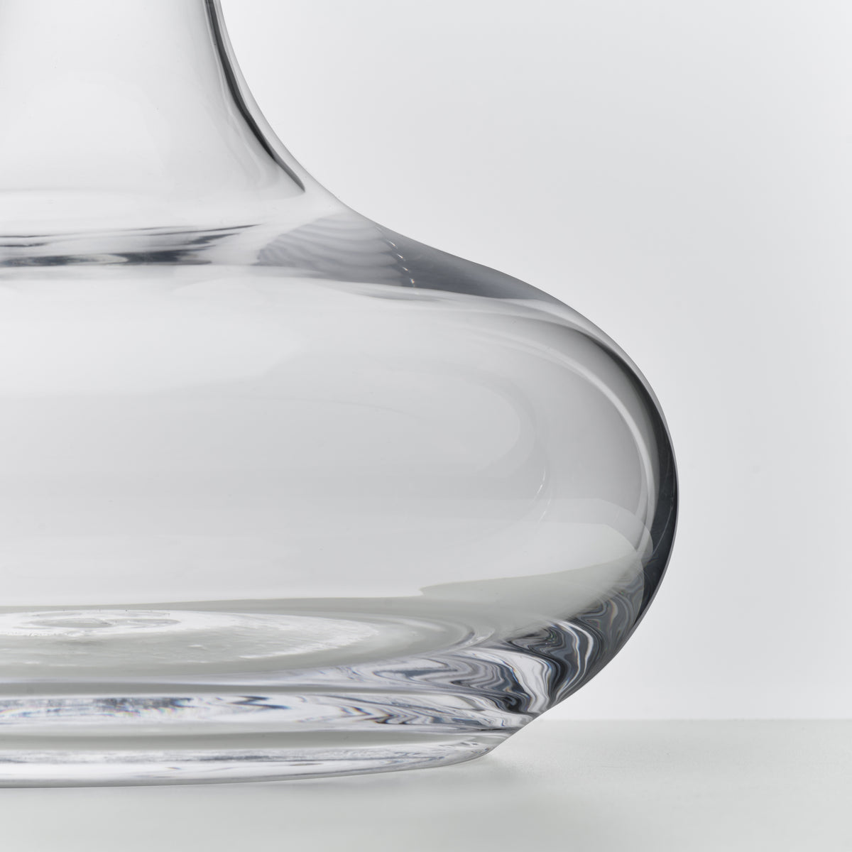 Clear glass wine decanter with curved sides and wide base, shown in close-up detail.