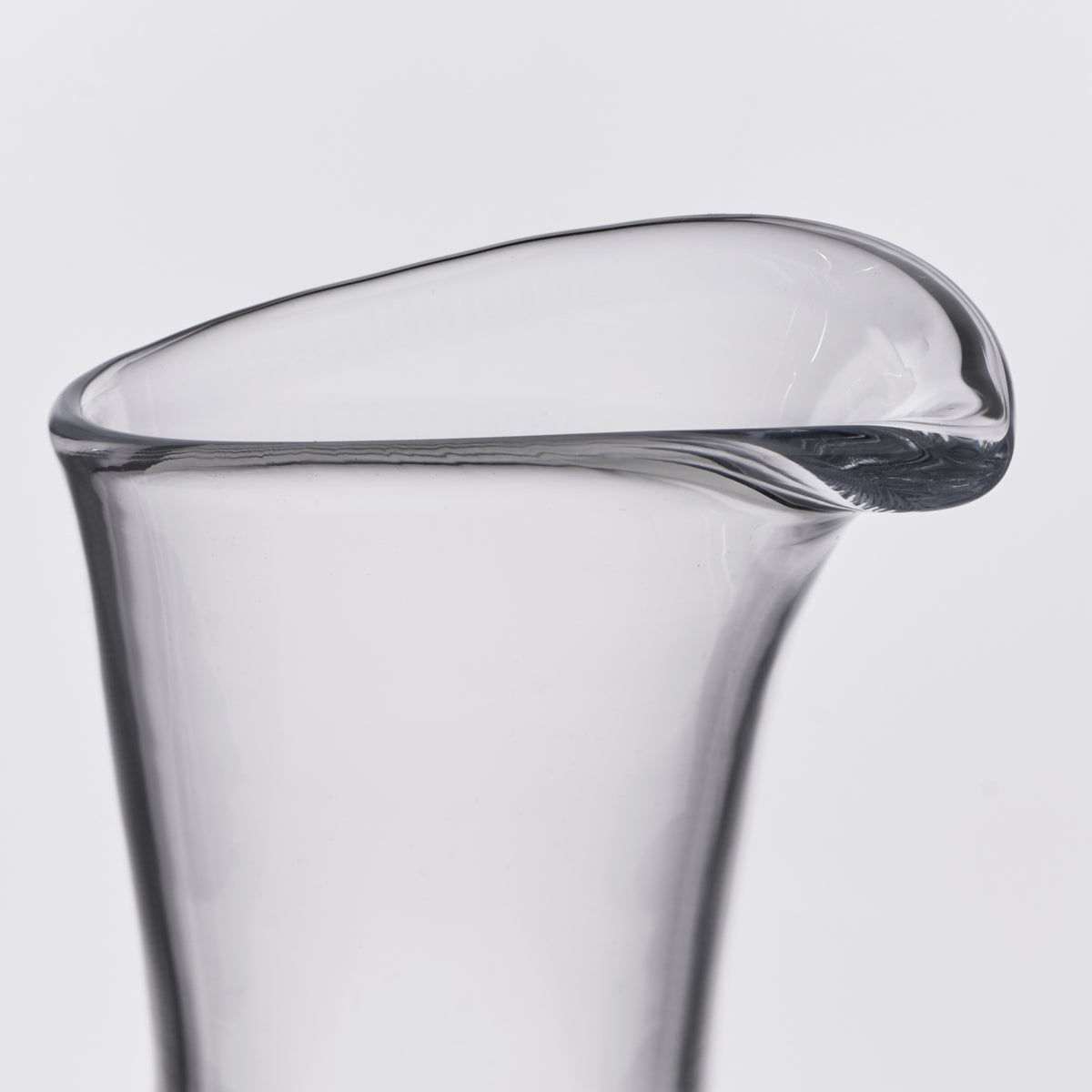 Clear glass carafe with angled pouring spout and curved rim.