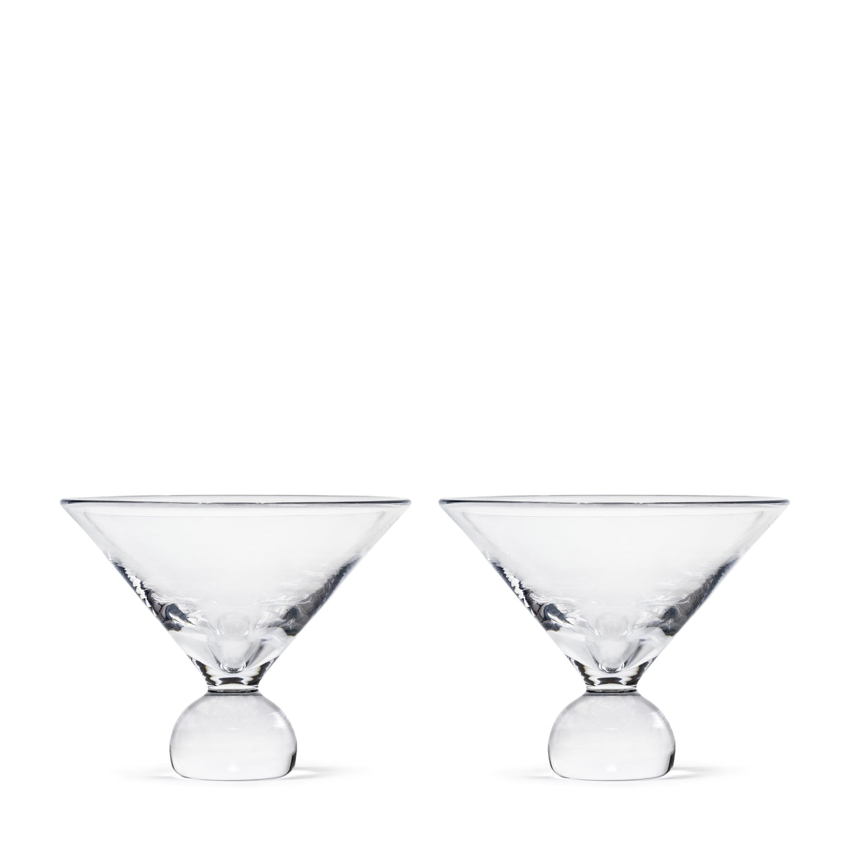 Two clear martini glasses with spherical bases side by side.