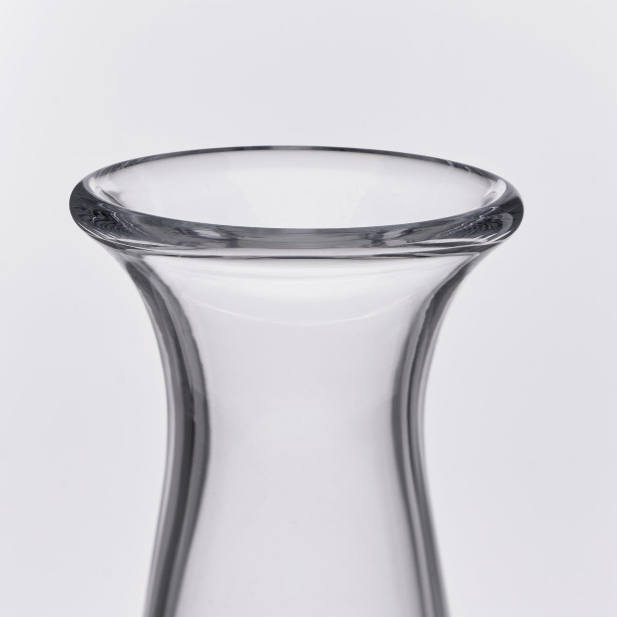 Clear glass decanter with curved sides and flared rim opening.