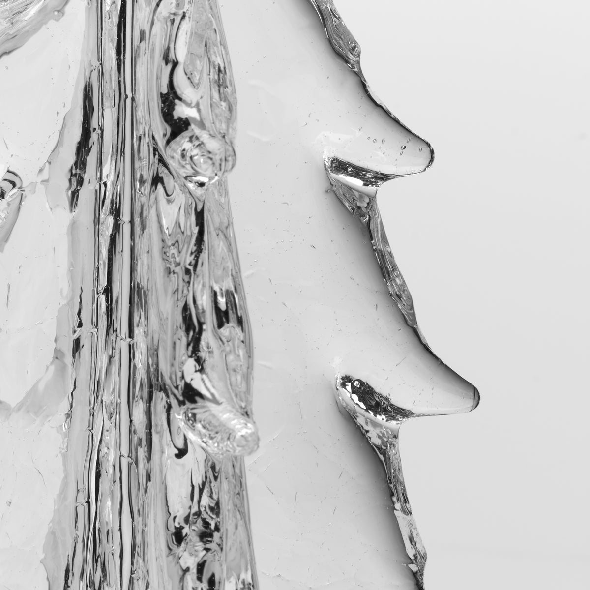 Clear glass four-sided vase with crackle texture and evergreen sprigs inside.