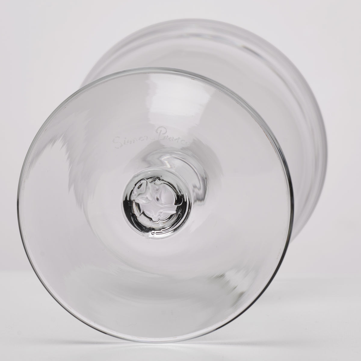 Two clear glass coupe glasses with wide bowls and etched branding, shown from above.