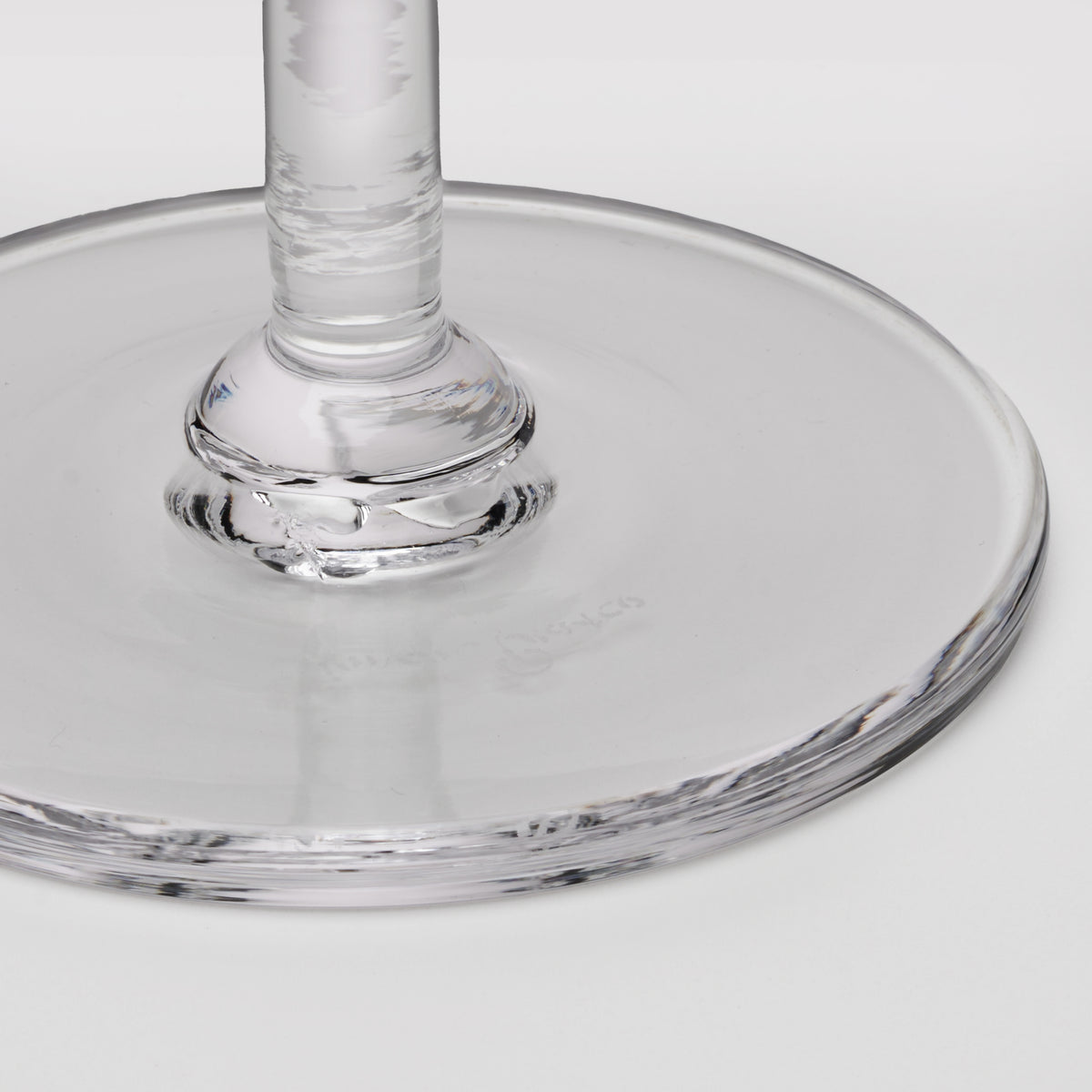 Clear glass coupe with wide shallow bowl and textured stem detail.