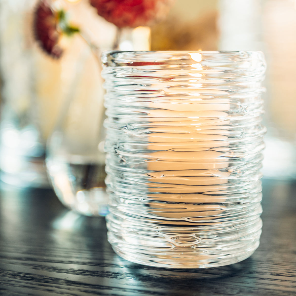 Clear glass hurricane candle holder with horizontal ribbed texture pattern.