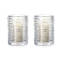 Two clear glass hurricane candles with textured horizontal ridges and cream-colored candles inside.