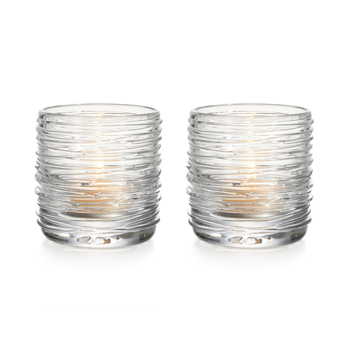 Two clear glass tealight holders with textured horizontal ridges and lit candles inside.