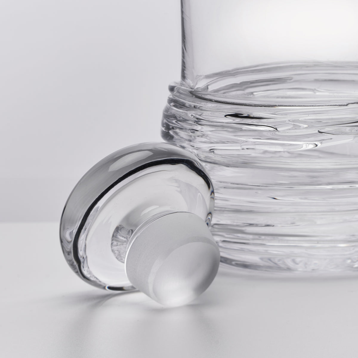 Clear glass decanter with horizontal ribbed texture and frosted stopper.
