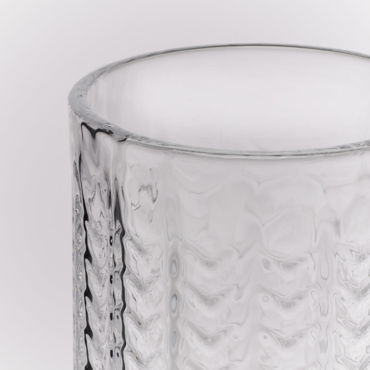 Clear glass Collins glass with geometric textured pattern and smooth rim.
