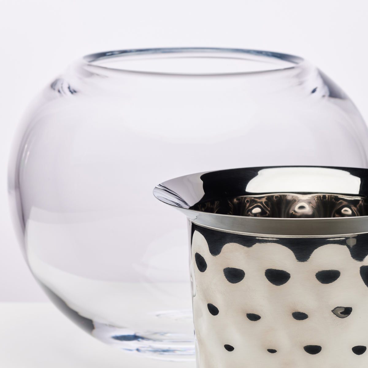 White glass wine chiller with metal rim and black polka dot ceramic insert with spout.