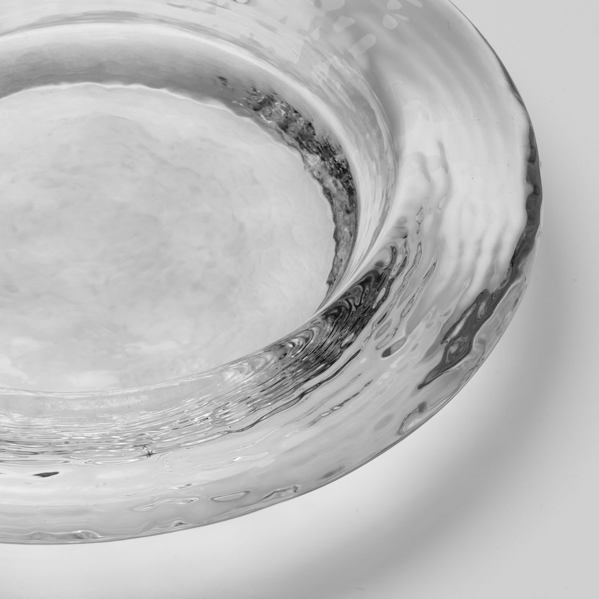 Clear glass coaster with swirled gray and black design detail around the rim.