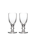 Two clear glass wine goblets with bulbous stems and round bases positioned side by side.