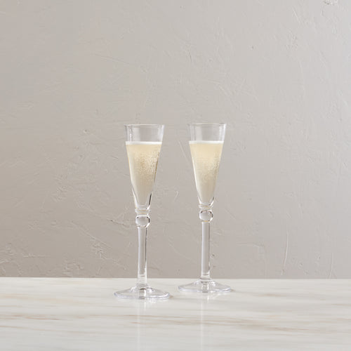 Two clear champagne flutes filled with sparkling champagne, displayed side by side.