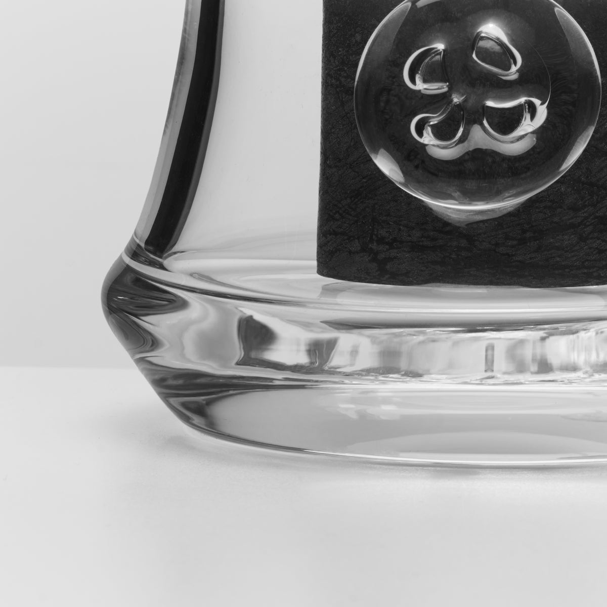 Clear glass bowl with decorative swirl handle and black gift box featuring embossed ornamental design.
