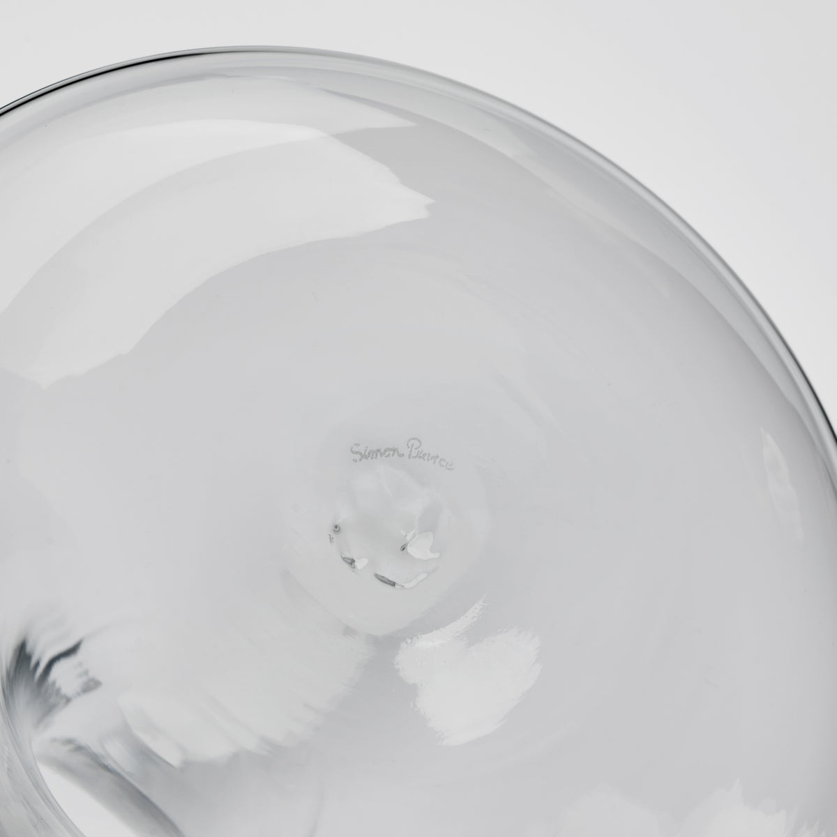 Clear glass decanter with curved body and maker's mark visible on interior base.